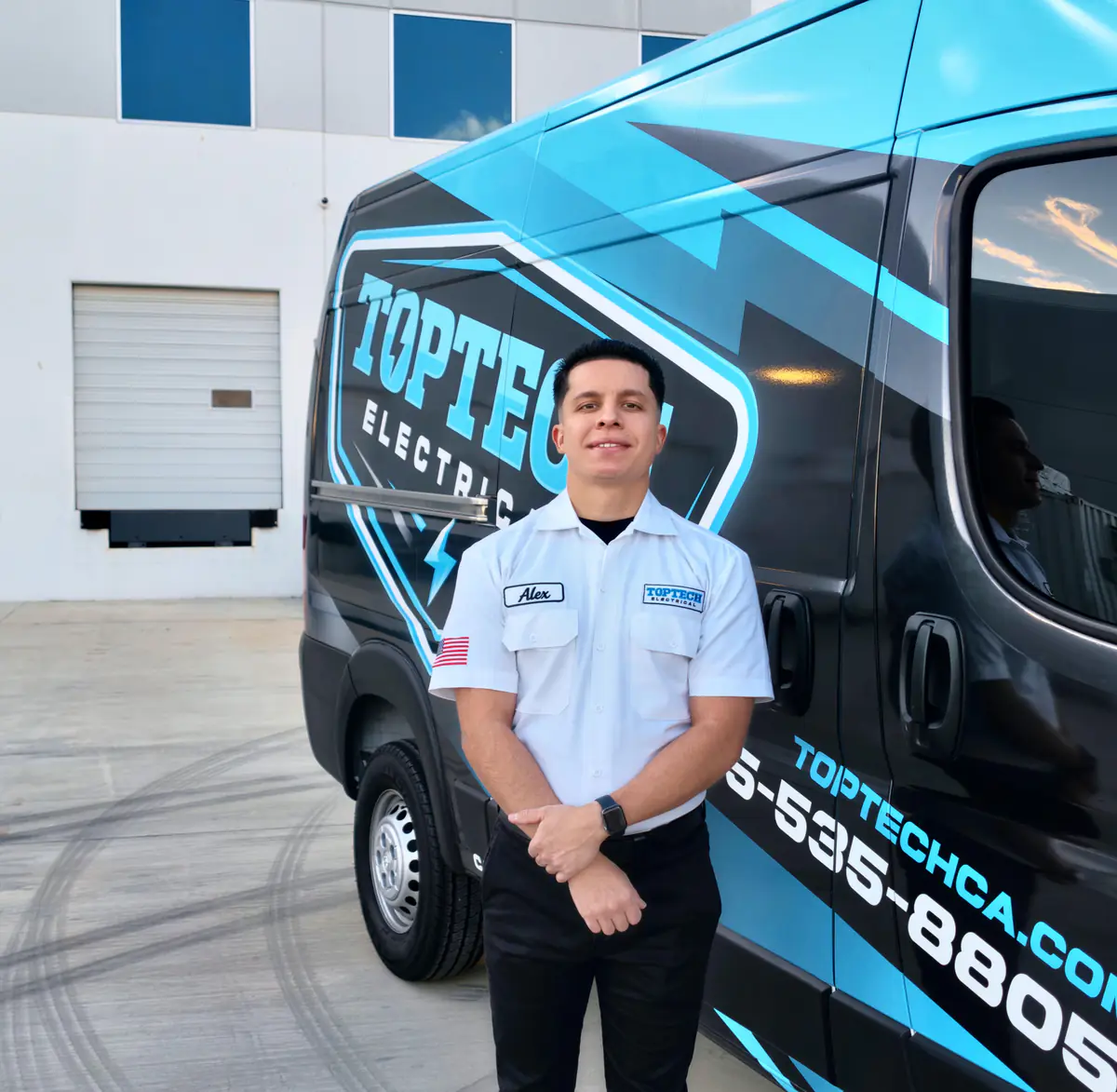 TopTech Electrical owner Alex Gonzalez in a white work shirt beside a branded service van