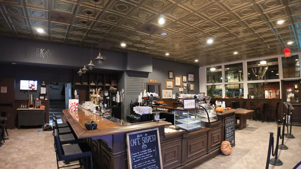 Recessed ceiling lights and pendant fixtures above the counter in a café